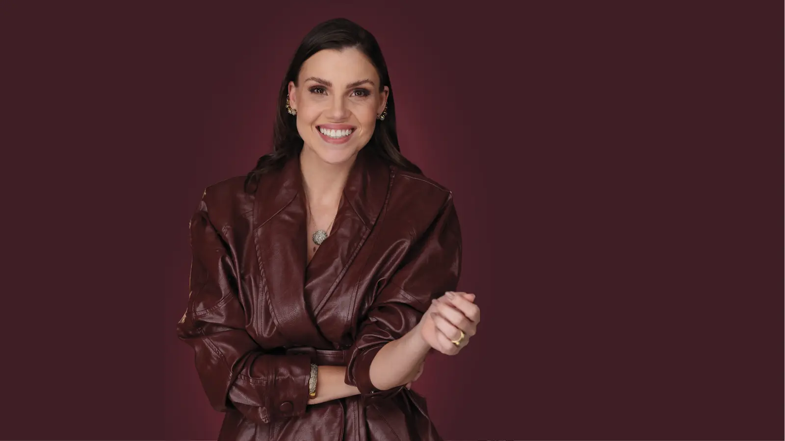 Dra. Luciana Bertão sorrindo, de casaco vinho, ao lado do monograma BL